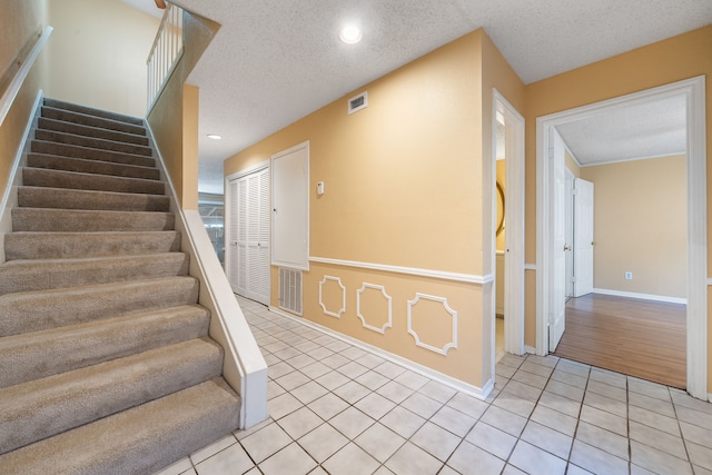 stairs with a textured ceiling and tile patterned floors