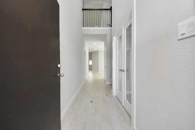 hallway with baseboards, a towering ceiling, and wood finished floors
