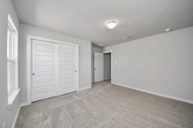 unfurnished bedroom featuring visible vents, carpet floors, a closet, baseboards, and multiple windows