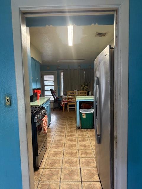 kitchen featuring blue cabinetry, stainless steel fridge, and range with gas stovetop