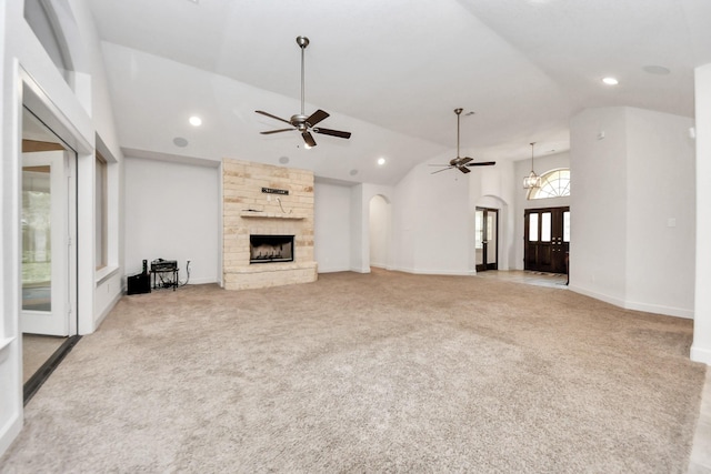 unfurnished living room with high vaulted ceiling, ceiling fan, light carpet, and a stone fireplace