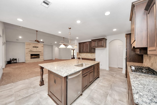 kitchen with stainless steel appliances, a kitchen island with sink, backsplash, and sink