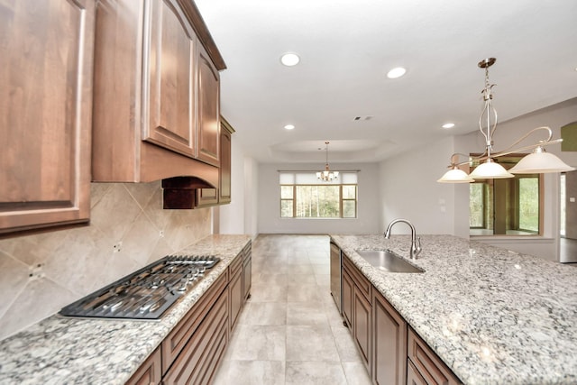 kitchen featuring sink, a raised ceiling, pendant lighting, and light stone counters