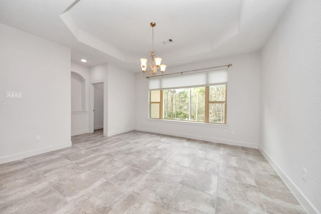 empty room featuring a raised ceiling and a notable chandelier