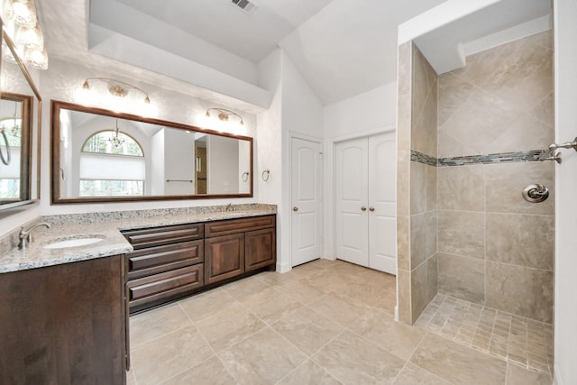 bathroom with a notable chandelier, tiled shower, and vanity