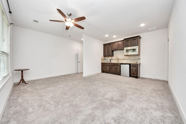 unfurnished living room featuring ceiling fan, light carpet, and sink