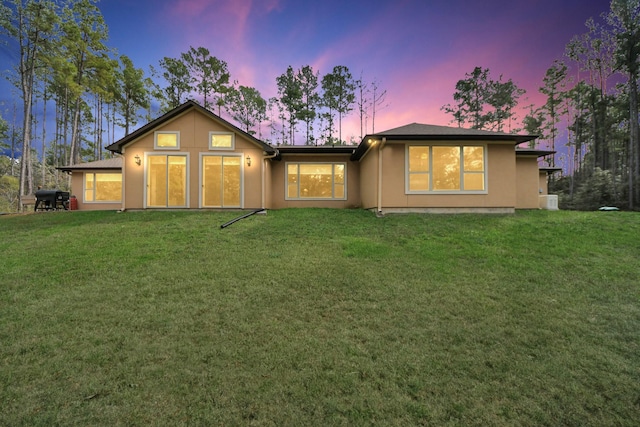 back house at dusk with a lawn