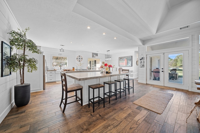 kitchen with french doors, dark wood-type flooring, a kitchen island, a kitchen bar, and white cabinets