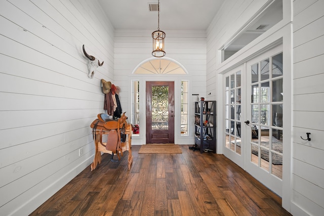 entryway with french doors, dark wood-type flooring, and wood walls