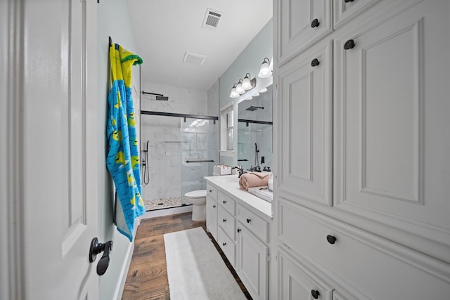 bathroom featuring hardwood / wood-style floors, vanity, toilet, and a shower with door