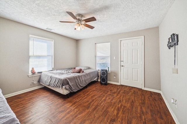 bedroom with a textured ceiling, ceiling fan, and dark wood-type flooring