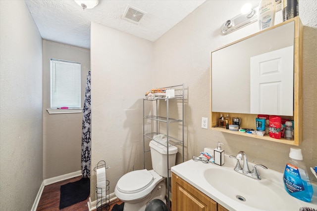 bathroom featuring vanity, wood-type flooring, a textured ceiling, and toilet