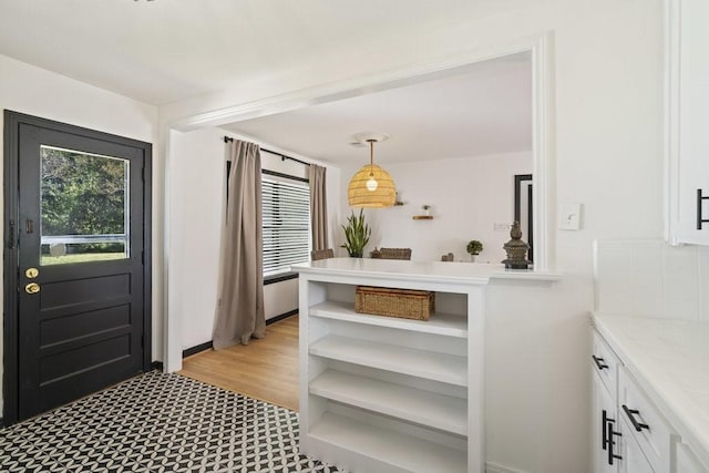 interior space featuring white cabinets, pendant lighting, light hardwood / wood-style flooring, and a wealth of natural light