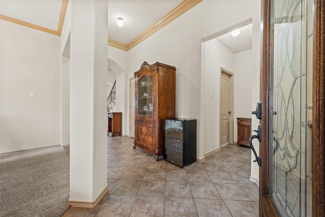 hallway with ornamental molding and light tile patterned floors