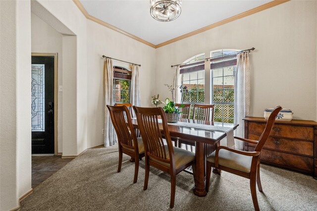 dining room featuring an inviting chandelier, ornamental molding, and dark colored carpet