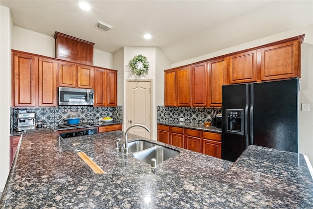 kitchen with tasteful backsplash, sink, black refrigerator with ice dispenser, and dark stone countertops