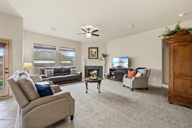 living room featuring ceiling fan, a tile fireplace, and light tile patterned floors