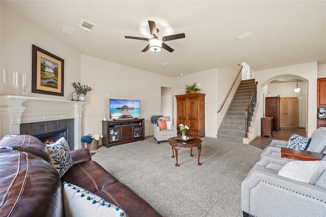 living room featuring a tiled fireplace, carpet, and ceiling fan