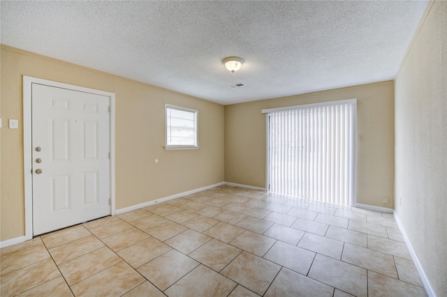 empty room featuring light tile patterned floors, a textured ceiling, and ornamental molding