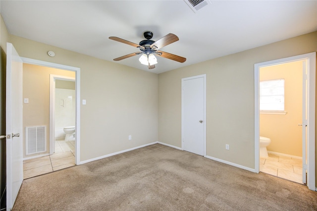 unfurnished bedroom featuring light carpet, a closet, ensuite bathroom, and ceiling fan