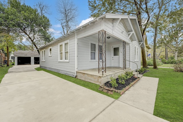 view of front of home featuring covered porch, a garage, an outbuilding, and a front yard