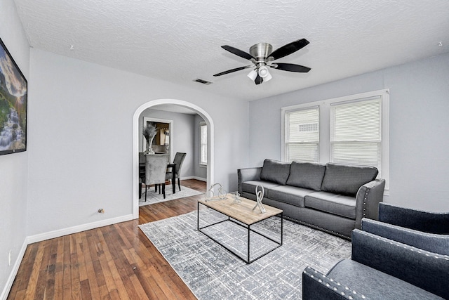 living room featuring hardwood / wood-style flooring, ceiling fan, and a textured ceiling