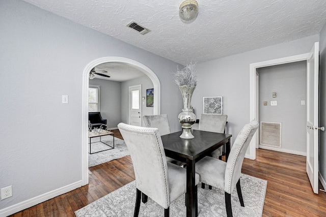 dining space featuring a textured ceiling, ceiling fan, and dark wood-type flooring