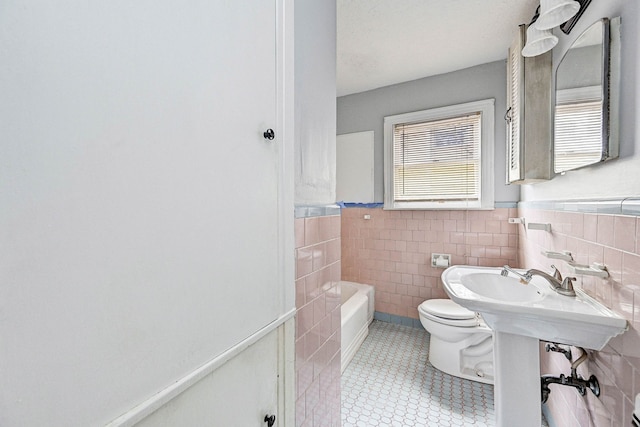 bathroom with a washtub, tile walls, and toilet