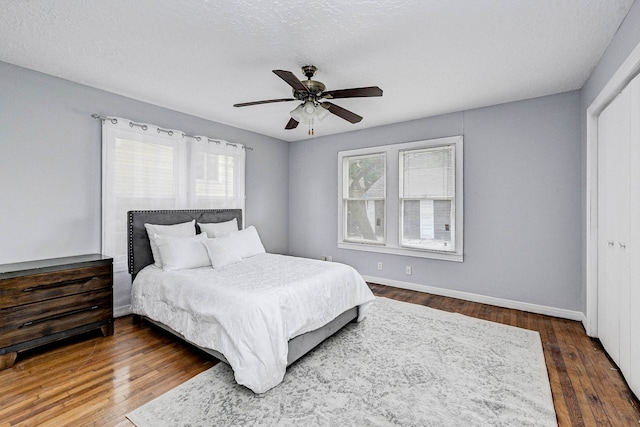 bedroom with dark hardwood / wood-style flooring, a closet, and ceiling fan