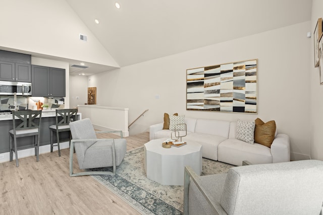 living room with light wood-type flooring and high vaulted ceiling