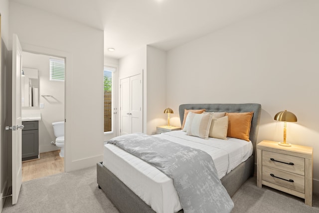 bedroom featuring light colored carpet, ensuite bathroom, and a closet