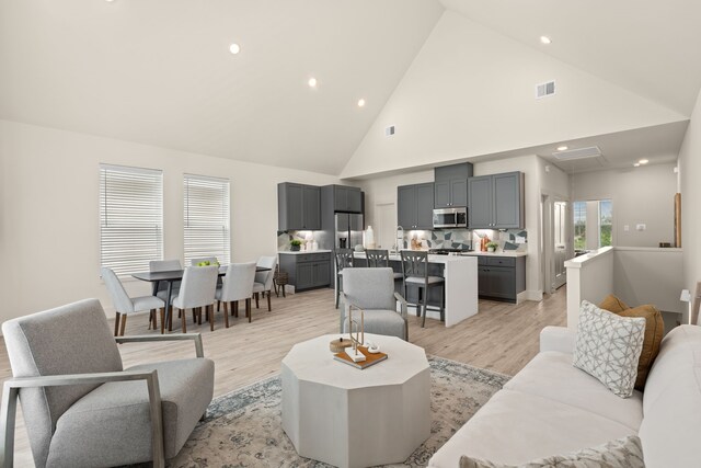 living room featuring high vaulted ceiling and light hardwood / wood-style floors