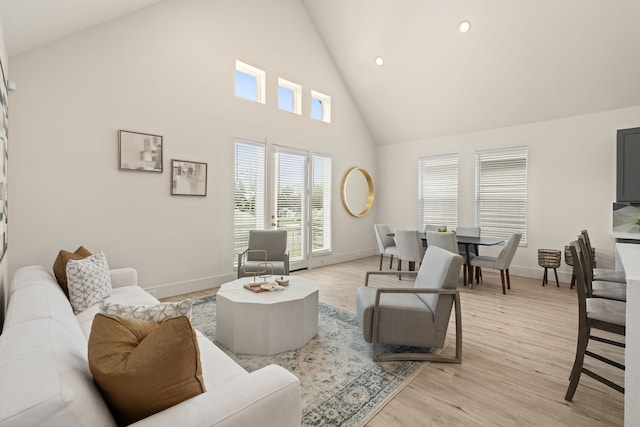 living room with high vaulted ceiling and light hardwood / wood-style flooring