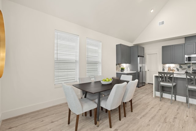 dining area featuring high vaulted ceiling and light hardwood / wood-style floors