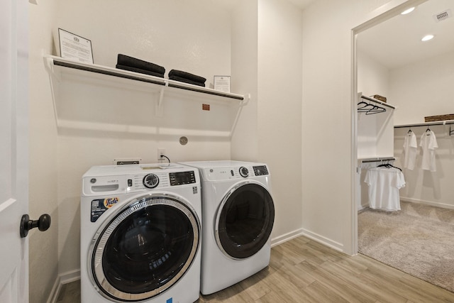 laundry area with separate washer and dryer and light hardwood / wood-style flooring