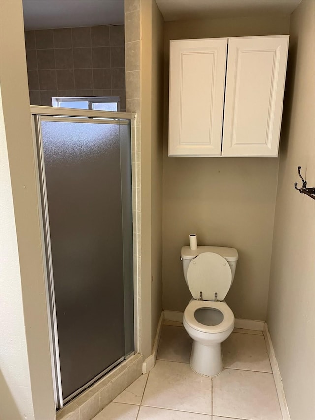 bathroom featuring toilet, a shower with door, and tile patterned flooring