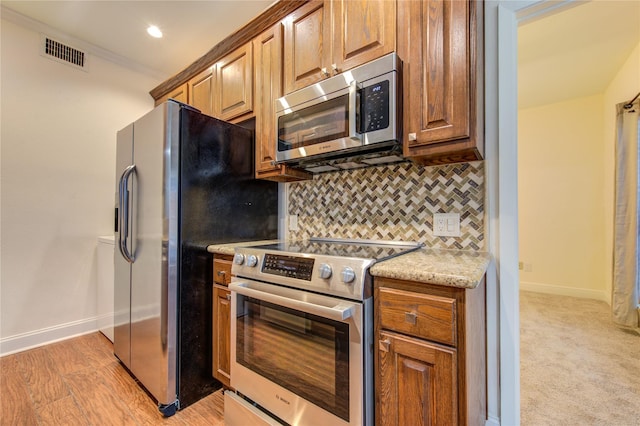 kitchen with decorative backsplash, crown molding, light colored carpet, and stainless steel appliances