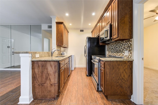 kitchen featuring backsplash, sink, ceiling fan, light stone countertops, and appliances with stainless steel finishes