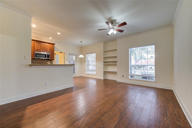 unfurnished living room with plenty of natural light, dark wood-type flooring, and ornamental molding