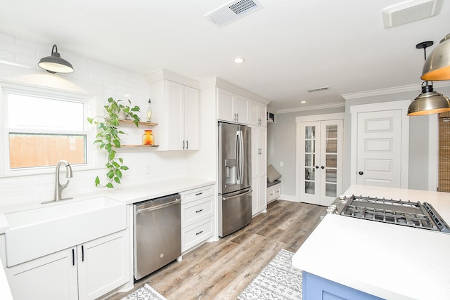 kitchen with white cabinetry, sink, french doors, appliances with stainless steel finishes, and light wood-type flooring