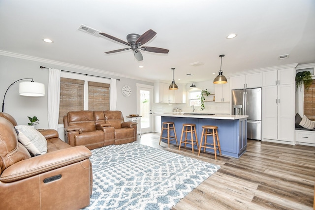 living room with light hardwood / wood-style floors, ceiling fan, ornamental molding, and sink