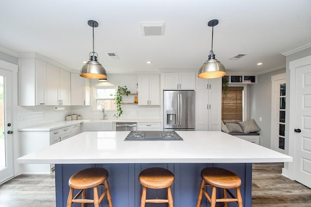 kitchen with a center island, white cabinetry, stainless steel appliances, and a breakfast bar area