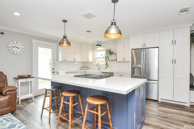 kitchen featuring pendant lighting, white cabinets, stainless steel appliances, and a kitchen island