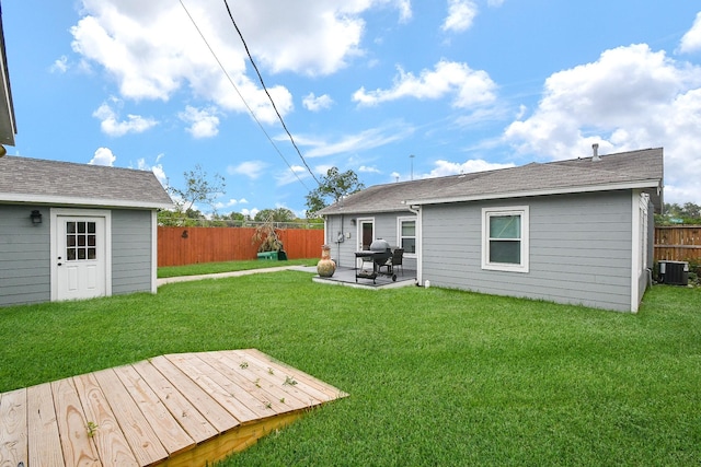 back of house with a lawn, a wooden deck, cooling unit, and a patio