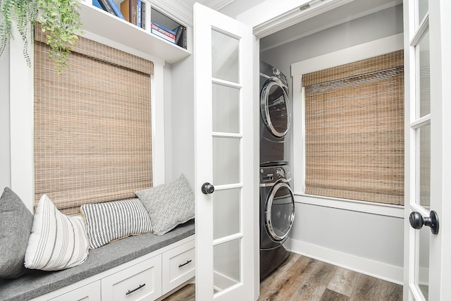 laundry area with hardwood / wood-style flooring and stacked washer / drying machine