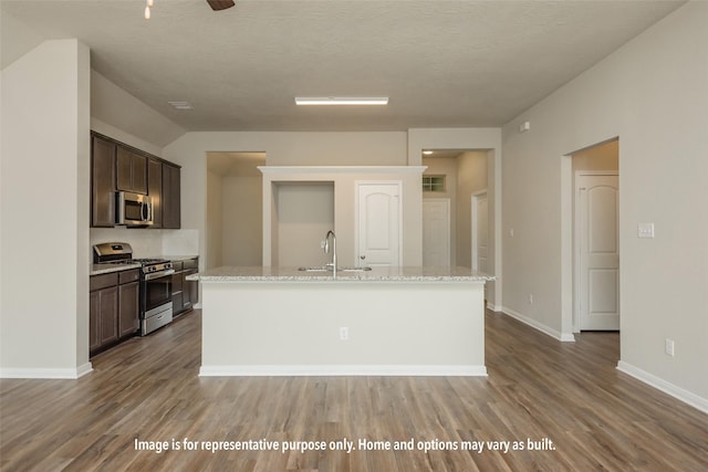 kitchen with hardwood / wood-style flooring, dark brown cabinetry, stainless steel appliances, and an island with sink