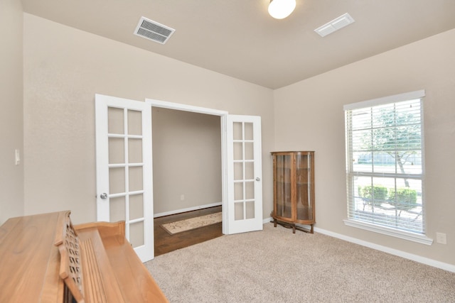 carpeted spare room featuring french doors