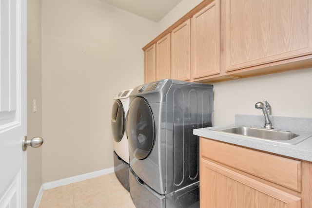 washroom with washing machine and dryer, sink, light tile patterned floors, and cabinets