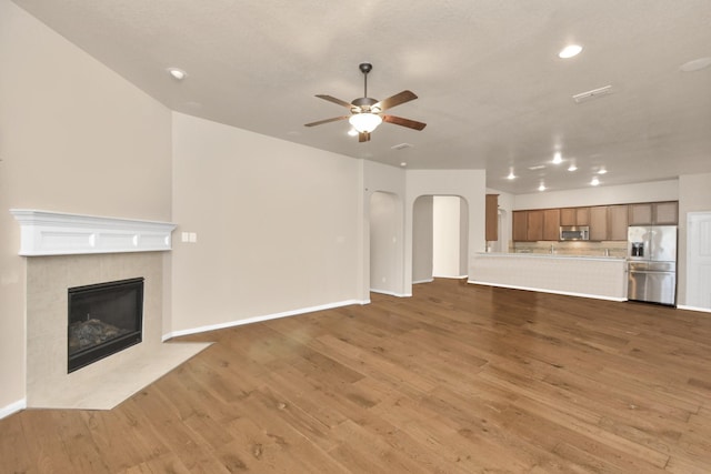 unfurnished living room featuring ceiling fan, a fireplace, and hardwood / wood-style floors