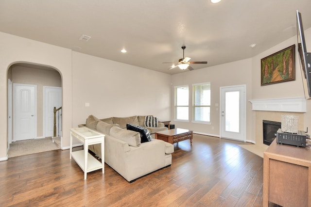 9614 Hideaway Green Dr, Richmond, TX 77406 - living room featuring a ceiling fan, a fireplace with flush hearth, wood finished floors, arched walkways, and recessed lighting